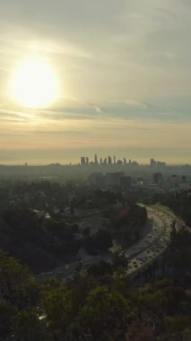 Los Angeles Skyline Sunrise 'da. Kaliforniya, ABD. Hava görüntüsü. Hollywood Tepelerinden Manzara. Drone geriye doğru uçuyor. Dikey Video