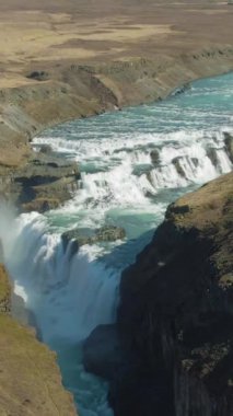 Güneşli yaz gününde Gullfoss Şelalesi. İzlanda. Hava görüntüsü. İHA ileri uçar, aşağı eğilir. Dikey Video