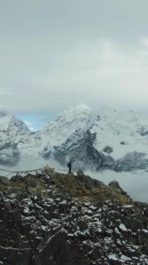 Nangartsang 'ın tepesindeki yürüyüşçü adam ve Ama Dablam Dağı. Himalaya, Nepal. Hava görüntüsü. Drone yörüngede. Dikey Video