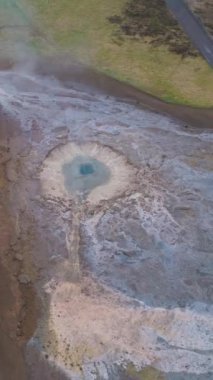 Strokkur Gayzer. İzlanda 'nın jeotermal doğası. Hava görüntüsü. Drone yörüngede. Dikey Video
