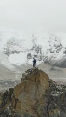 Kalapatthar Dağı 'nın tepesindeki gezgin adam Khumbu Buzul, Everest ve Nuptse' ye bakıyor. Himalaya, Nepal. Hava görüntüsü. Drone yörüngede. Dikey Video