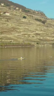 Cenevre Gölü Turkuaz Gününde Kayak yapan İki Adam. İsviçre Alpleri, İsviçre. Drone yörüngede. Dikey Video