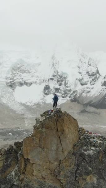 カラパタリス山の頂上にあるハイカーマンは クエストとナプトゥスの氷河を眺めています ネパールのヒマラヤ アリアルビュー ドローンが軌道を回っている バーティカルビデオ — ストック動画