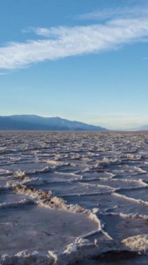 Güneşli günde Badwater Havzası. Tuz Kabuğu oluşumları ve Bulutlu Mavi Gökyüzü. Death Valley Ulusal Parkı. Kaliforniya, ABD. Hızlandırılmış Panning Zaman Hızı. Dikey Video