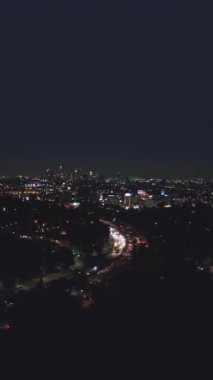 Gece vakti Los Angeles Skyline. Kaliforniya, ABD. Hava görüntüsü. Hollywood Tepelerinden Manzara. Drone İleri Uçuyor. Dikey Video