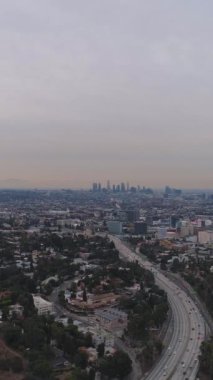 Sabah Los Angeles 'ta. Otobanda trafik vardı. Kaliforniya, ABD. Hava görüntüsü. Hollywood Tepelerinden Manzara. Drone geriye doğru uçuyor. Dikey Video