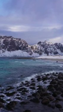 Uttakleiv Sahili Norveç Denizi ve Kışın Dağları. Lofoten Adaları, Norveç. Hava görüntüsü. Drone İleri Uçuyor. Dikey Video