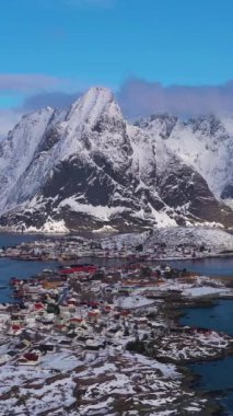 Kışın Reine Köyü ve Dağları. Olstinden Tepesi. Moskenes, Lofoten Adaları. Norveç 'in manzarası. Hava görüntüsü. Drone yörüngede. Dikey Video
