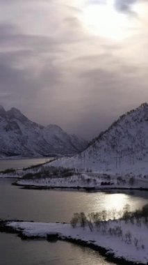 Laupstadosen Fjord ve Dağları kışın. Lofoten Adaları, Norveç. Hava görüntüsü. Drone Yana ve Yukarı Uçuyor. Dikey Video