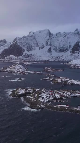 冬のハムノイ村と山々 ノルウェーの海と嵐の空 ノルウェーのロフォンテ諸島 モスケン アリアルビュー ドローン フライズ サイドウェイ バーティカルビデオ — ストック動画