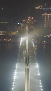 Guangzhou 'daki köprü, geceleri araba trafiği. Guangdong, Çin. Hava görüntüsü. Drone geriye doğru uçuyor. Dikey Video