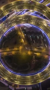 Gece vakti Nanpu Yolu kavşağı aydınlandı. Trafik Çemberi. Şangay, Çin. Hava Dikey Tepetaklak Hiper Geçiş, Zaman Hızı. İnsansız hava aracı rotasyonu. Dikey Video