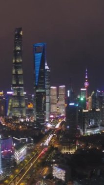 Gece Şangay Şehir Manzarası. Lujiazui Bölgesi ve Aydınlanmış Skyline. Çin. Hava görüntüsü. Drone Yana ve Yukarı Uçuyor. Dikey Video