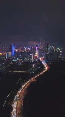 Geceleyin Shenzhen Şehri. Futian Bölgesi Şehir Skyline ve Shenzhen Körfezi. Guangdong, Çin. Hava Çekimi, İHA Aşağı ve Geri Uçuyor. Dikey Video