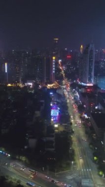 Geceleyin Shenzhen Şehri 'ni aydınlattı. Futian ve Luohu Bölgesi. Çin. Hava görüntüsü. Drone Yana ve Yukarı Uçuyor. Dikey Video