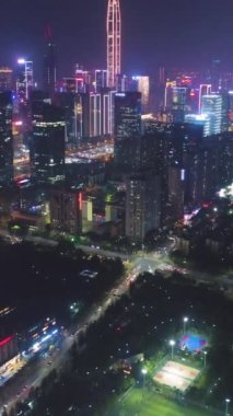 Geceleyin Shenzhen Şehri 'ni aydınlattı. Futian Bölgesi. Çin. Hava görüntüsü. Drone İleri Uçuyor, Eğil. Şutu göster. Dikey Video