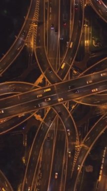 Gece Karmaşık Yol Üstgeçidi. Şangay Şehri. Çin. Havadan Yukarıdan Aşağı Görünümü. İnsansız Hava Aracı Dönüyor ve Aşağı Uçuyor. Dikey Video