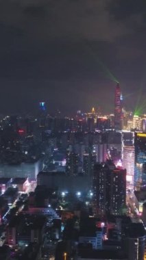 Shenzhen, Çin. Işık Gösterisi Gecesinde Aydınlanmış Şehir. Futian ve Luohu Bölgesi. Guangdong 'da. Hava görüntüsü. Drone Yana ve Yukarı Uçuyor. Dikey Video