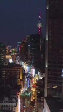 Gece Nanjing Yolu 'ndaki insanlar. Huangpu bölgesindeki yaya sokağı. Şangay, Çin. Hava görüntüsü. Drone yukarı uçuyor, kamera aşağı eğiliyor. Dikey Video