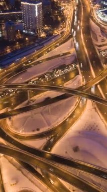 Urban City 'de Kış Gecesinde Aydınlatılmış Yol Kavşağı ve Araba Trafiği. Üstgeçit. Drone yörüngede. Hava Hiper Hatası. Dikey Video