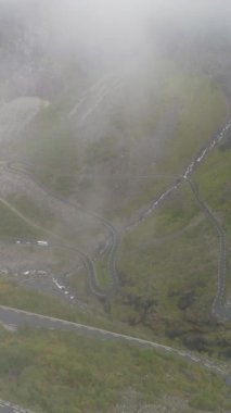 Trol Bayramı - Norveç 'in ünlü Trol Yolu. Siste Eğri Dağ Yolu. Hava görüntüsü. Şutu göster. Drone 's Flying in Mist. Dikey Video