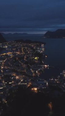 Norveç 'teki Alesund şehrini gece aydınlatmış. Hava görüntüsü. Drone yörüngede dönüyor. Dikey Video
