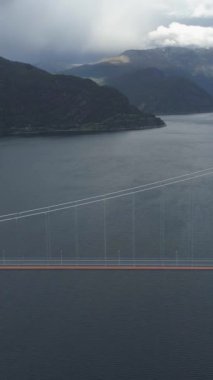 Norveç 'te geçen arabayla Hardangerfjord' un karşısındaki Uzun Hardangerous Askısı Köprüsü. Fiyort ve Dağlar. Hava görüntüsü. İnsansız hava aracı Yanlamasına uçuyor. Dikey Video