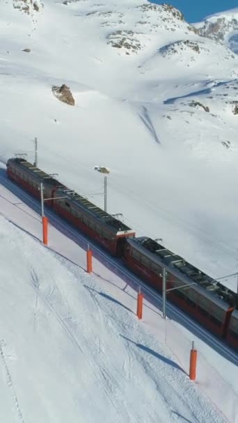 ゼルマット スイスツーラーランド February 2019 晴れた冬の日にコグ鉄道 スイスアルプス スイス アリアルビュー ドローンが軌道を回っている バーティカルビデオ — ストック動画