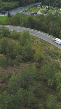 Beyaz Karavan Otomobili Sonbahar Günü Norveç 'te Country Road' a çıkıyor. Ağaçlar ve Şehir. Hava görüntüsü. İnsansız hava aracı Yanlamasına uçuyor. Dikey Video