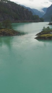 Turkuaz Su ve Yeşil Adalı Lovatnet Gölü. Norveç 'in güzel doğası. Hava görüntüsü. Drone yörüngede ve yükseliyor. Dikey Video