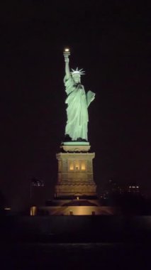 New York 'ta Gece Özgürlük Heykeli. Sudan görüntü. Yörüngede. Orta boy shot. Dikey Video