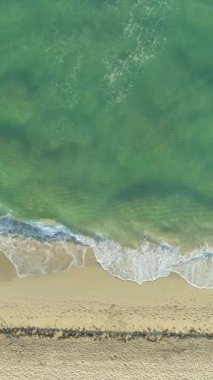 Sunny Morning 'de Dalgalar ve Sandy Beige Sahili' yle deniz. Havadan Yukarıdan Aşağı Görünümü. Dikey Video