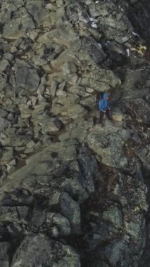 Yürüyen Polonyalılarla gezen adam Norveç 'in Karlı Dağları' ndaki Cliff 'in yanında duruyor. Hava görüntüsü. Drone yörüngede dönüyor. Dikey Video