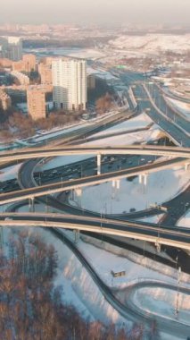 Şehir Şehri 'nde Sunny Winter Day' de kompleks üstgeçit ve yol trafiği. Hava görüntüsü. Drone Yörüngede ve Yukarı Uçuyor, Kamera Eğiliyor. Dikey Video