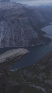 Norveç 'teki Trolltunga Kayalıkları. Yazın ünlü Trol Dili Rock 'ı. Havadan İfşaat Çekimi. İHA ileri uçuyor, Kamera yukarı eğiliyor. Dikey Video