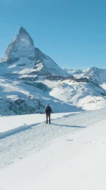 Matterhorn Dağı Kış Günü ve Hiker Man. İsviçre Alpleri, İsviçre. Hava görüntüsü. Drone yörüngede. Dikey Video