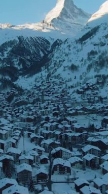Güneşli Kış Günü 'nde Zermatt Köyü ve Matterhorn Dağı. İsviçre. Hava görüntüsü. Şutu göster. İHA ileri uçuyor, Kamera yukarı eğiliyor. Dikey Video