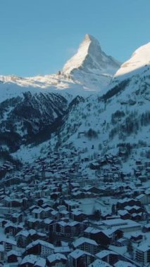 Zermatt Village ve Matterhorn Dağı, Sunny Winter Morning 'de. İsviçre. Hava Aracı Atışı. Drone Yana ve Yukarı Uçuyor. Dikey Video