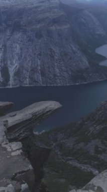 Norveç 'teki Trolltunga Dağı Kayalıkları. Yazın ünlü Trol Dili Rock 'ı. Hava görüntüsü. Drone ileri uçuyor, Kamera aşağı eğiliyor. Dikey Video