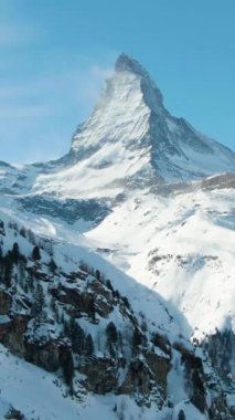 Kış Günü 'nde Matterhorn Dağı. İsviçre Alpleri. Kar yağışlı İsviçre. Hava görüntüsü. Orta boy shot. Drone geriye doğru uçuyor. Dikey Video
