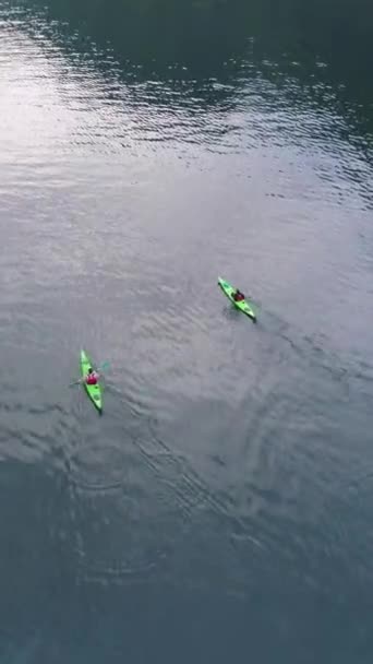ジレンジャーフィヨルドのターコイズ水の2つの緑のカヤック ノルウェー アリアルビュー ドローンが前方に向かって飛んでいる カメラが傾いている バーティカルビデオ — ストック動画