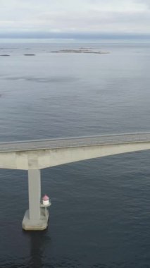 Motorlu Araç Storseisundet Köprüsü 'nde seyahat ediyor. Norveç 'teki Atlantik Okyanusu Yolu, Güneşli Yaz Günü. Hava görüntüsü. İnsansız hava aracı Yanlamasına uçuyor. Dikey Video