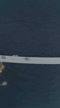 Arabalar Norveç 'te Atlantik Okyanus Yolu' na gidiyor. Havadan Yukarıdan Aşağı Görünümü. İnsansız hava aracı Yanlamasına uçuyor. Dikey Video