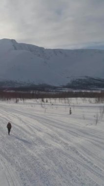 İnsan, güneşli kış gününde dağlarda yürüyüş yapıyor ve Polonyalıları kullanıyor. Hava görüntüsü. Drone yörüngede dönüyor. Atış ayarlanıyor. Yavaş Hareket.. Dikey Video
