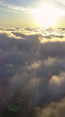 Genç bir kadın, güneş doğarken pembe bulutların üzerinde, dağ platosunda koşuyor. Dikey Video