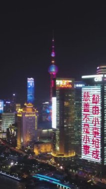 Şangay, Çin - 12 Ocak 2018: Lujiazui İlçesi gökdelenleri geceleyin aydınlandı. Şangay Şehir Merkezi. Hava görüntüsü. İnsansız hava aracı yan yana uçuyor. Atış ayarlanıyor. Dikey Video