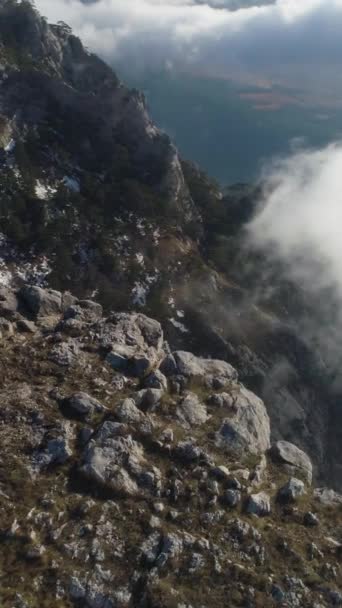 背着背包的远足者正在云彩之上的陡峭山崖上行走和站立 空中风景 无人机在轨道上垂直录像 — 图库视频影像