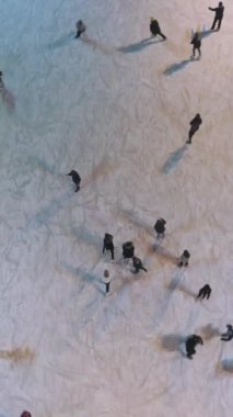 İnsanlar akşamları aydınlık buz pateni pistinde kayıyorlar. Havadan yukarıdan aşağıya doğru. Çekim başlıyor. Drone ileri uçuyor. Dikey Video