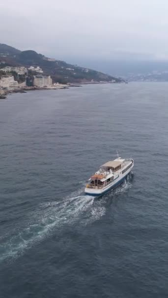小さな白いクルーズ船が海岸線近くで航海している 空からの眺め バーティカルビデオ — ストック動画