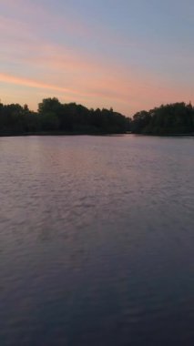 Güneşli bir sabahta gölün üzerinde hızlı alçak açı uçuyor. Hava görüntüsü. Dikey Video